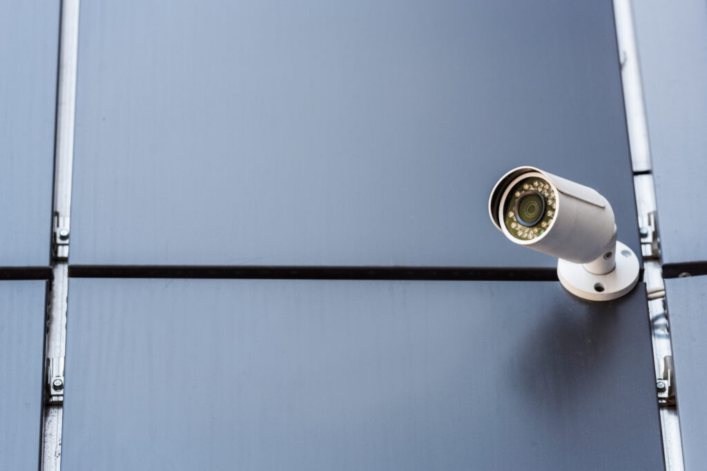 White security camera mounted in the corner of a grey wall for an office building